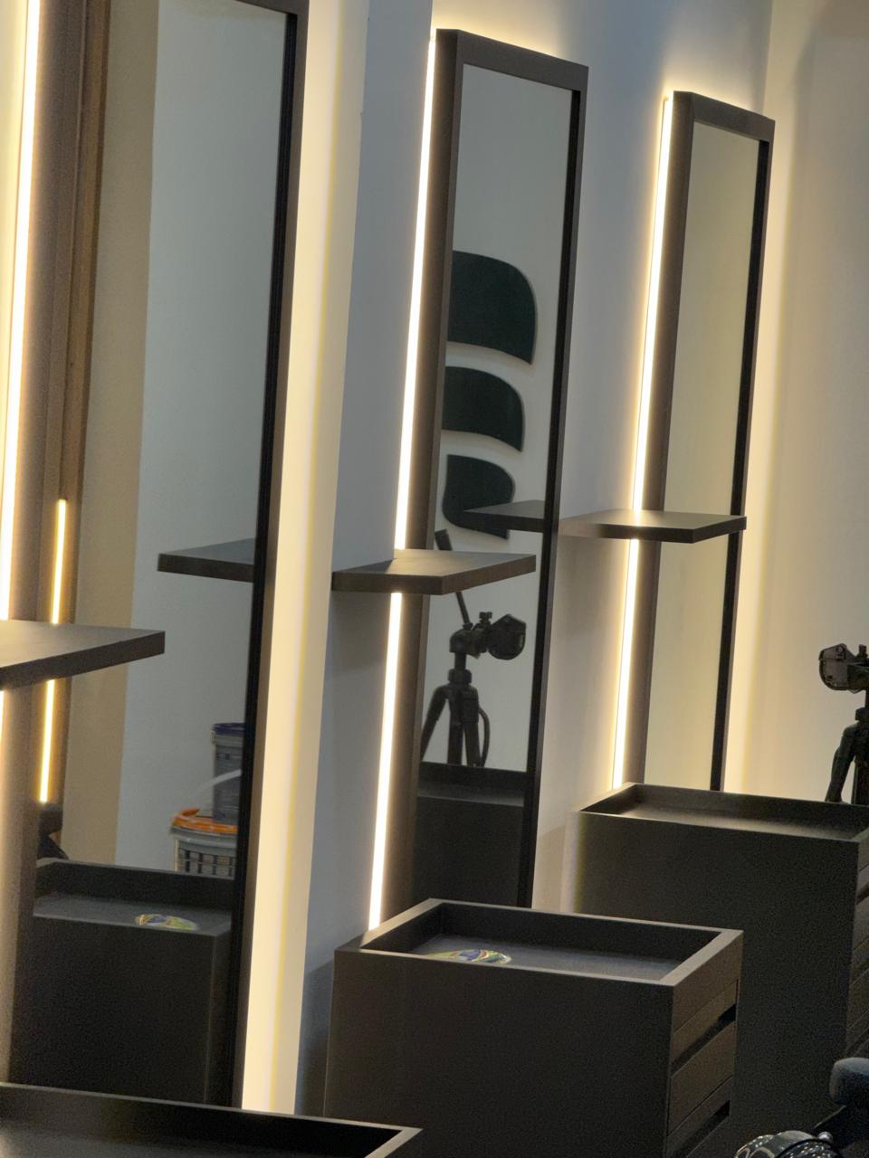 Espelhos com iluminação de LED e bancadas pretas no salão da Fícus