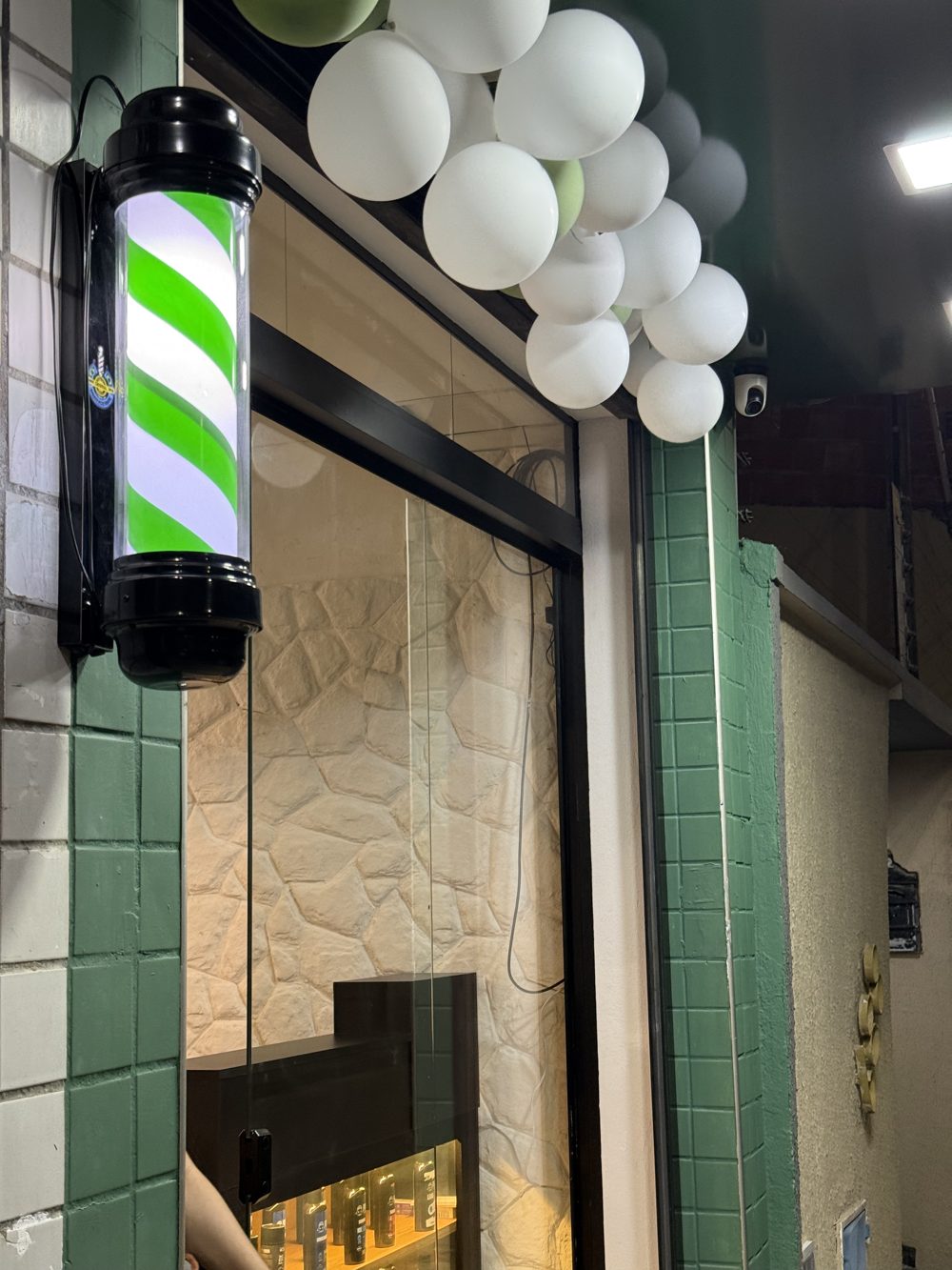 Fachada com azulejos verdes e poste de barbearia