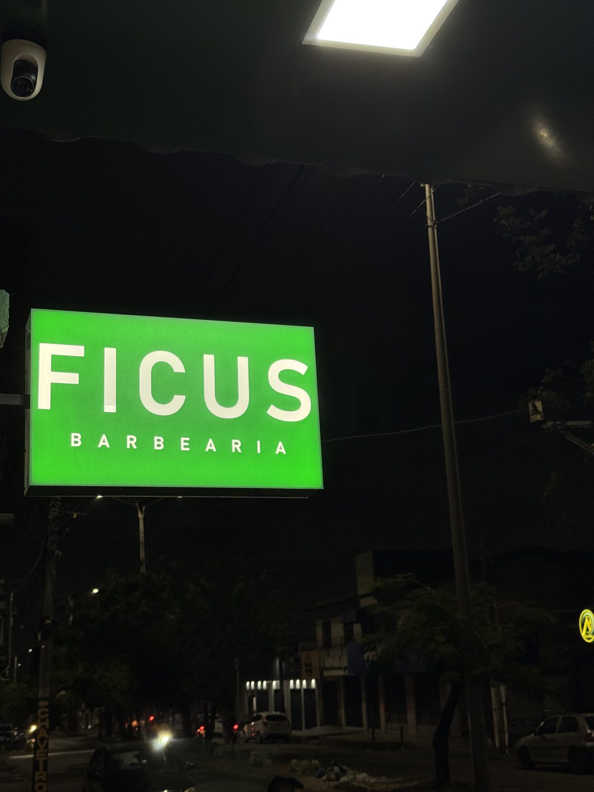 Letreiro verde iluminado da Fícus Barbearia à noite